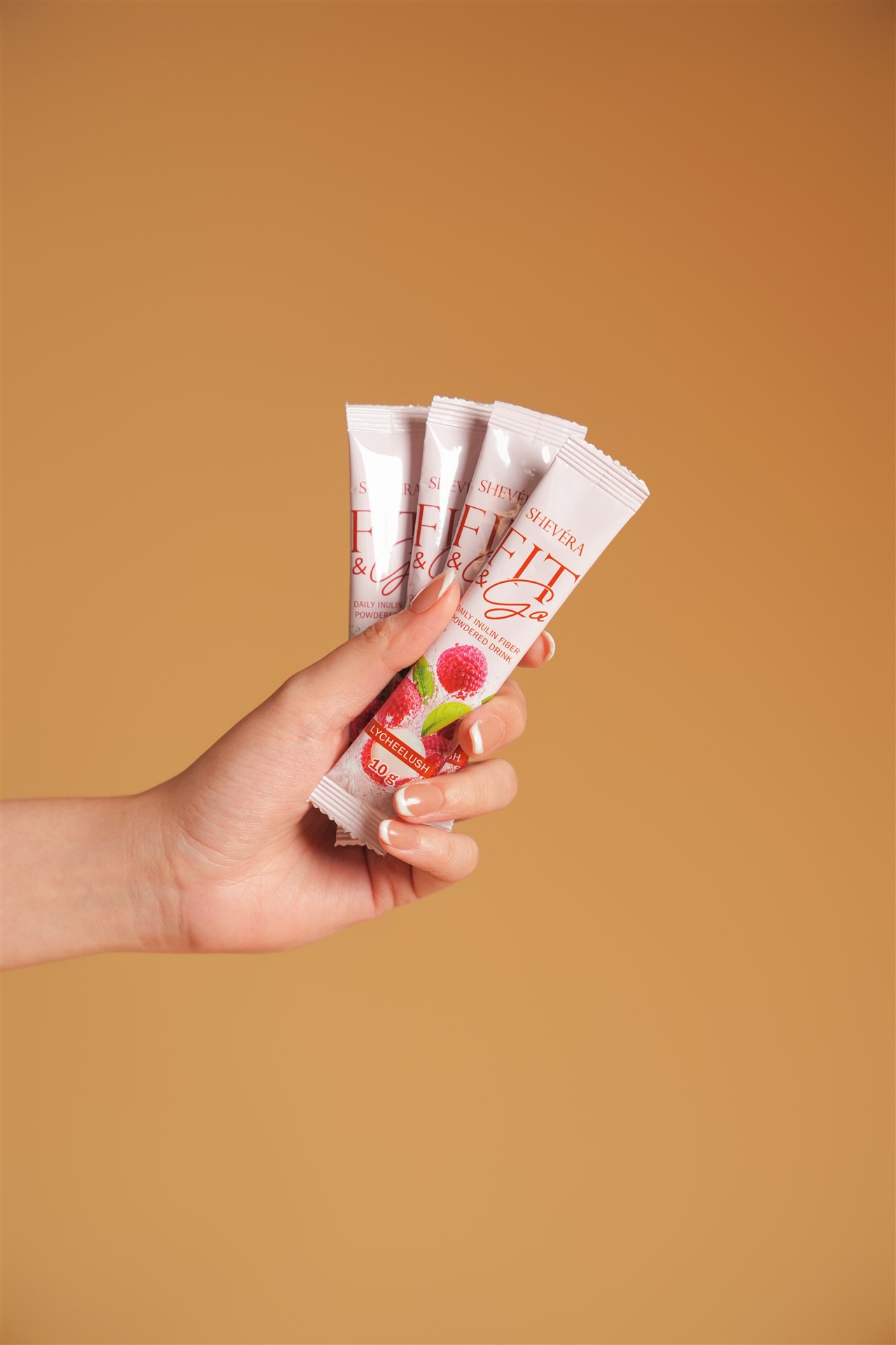 A hand holding Shevéra Fit and Go Lycheelush sachets